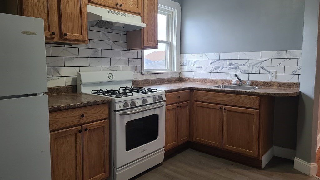 672 2nd Street Fall River, MA 02721 - Photo 10 of 16 a kitchen with granite countertop a sink stove and cabinets