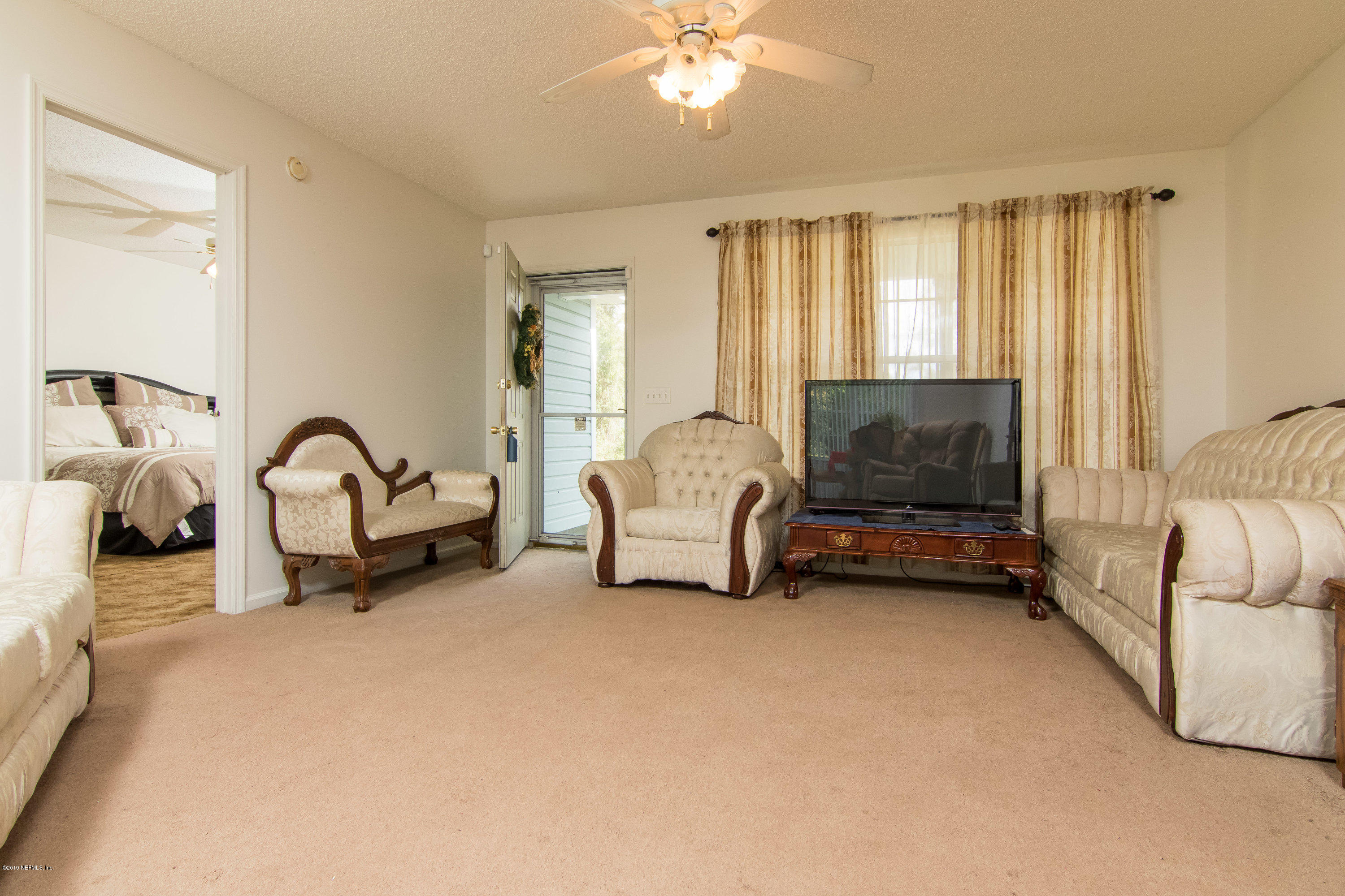 6345 Armstrong Road Elkton, FL 32033 - Photo 12 of 26 a living room with furniture a flat screen tv and a large window