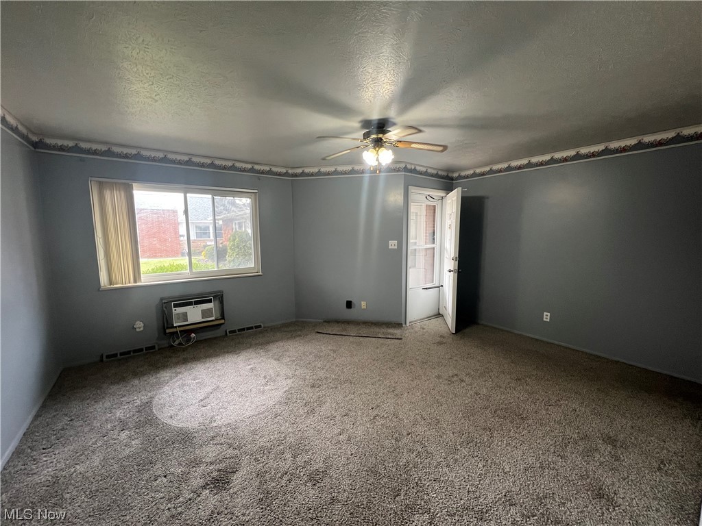 5651 Broadview Road, Unit C 07 Cleveland, OH 44134 - Photo 5 of 15 Carpeted spare room with a wall unit AC, a textured ceiling, and ceiling fan