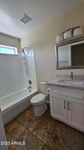 a bathroom with a granite countertop toilet sink and mirror