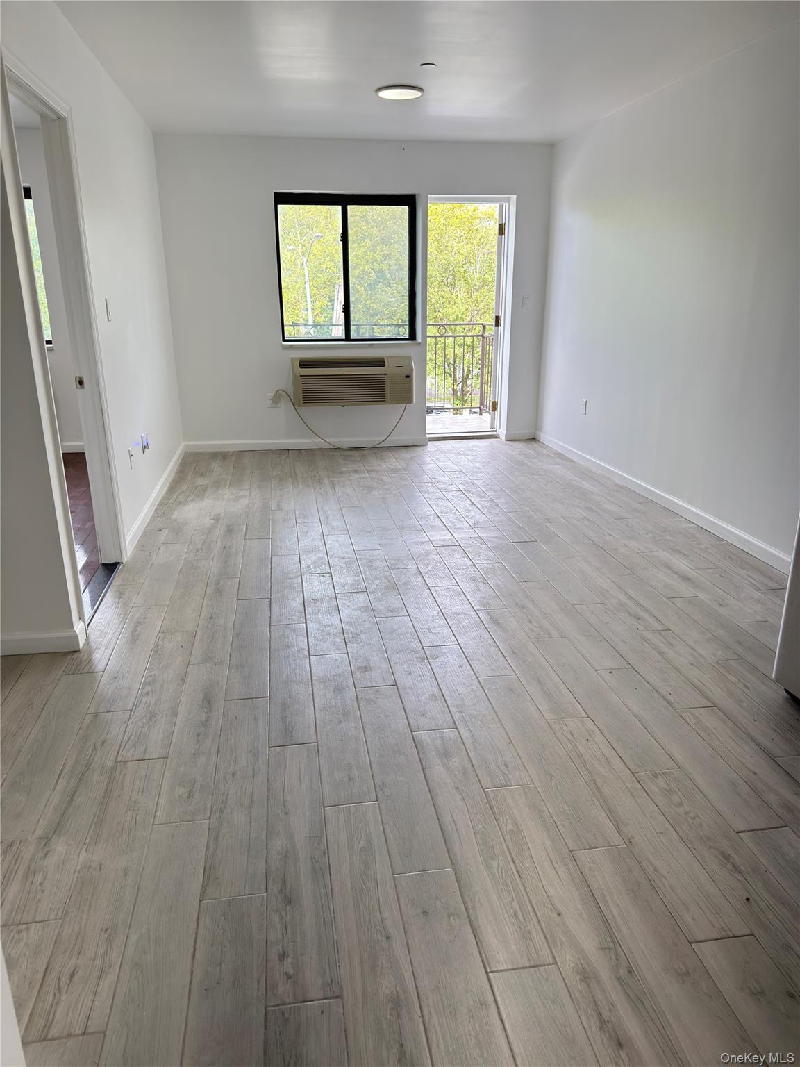 49-10 111th Street, Unit 3A Queens, NY 11368 - Photo 2 of 8 an empty room with wooden floor and windows