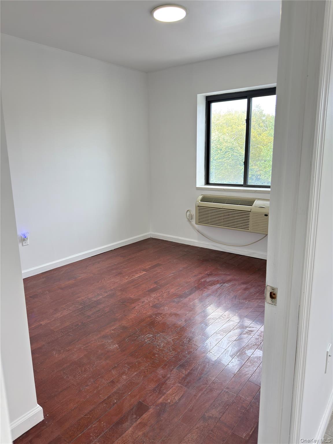 49-10 111th Street, Unit 3A Queens, NY 11368 - Photo 4 of 8 an empty room with wooden floor and windows