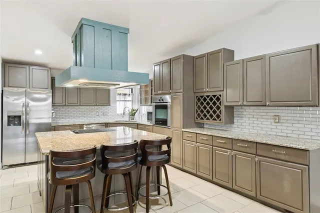 a kitchen with granite countertop a table chairs stainless steel appliances and cabinets