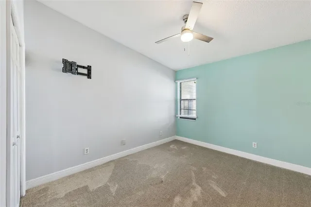 an empty room with a chandelier fan and windows