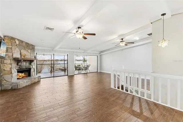 a view of an empty room with wooden floor and a fireplace