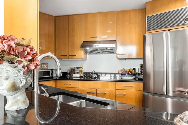 a kitchen with stainless steel appliances granite countertop a refrigerator a stove and a wooden cabinets