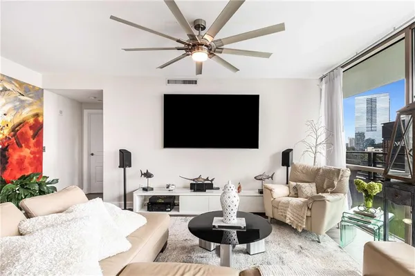 a living room with furniture a flat screen tv and a large window