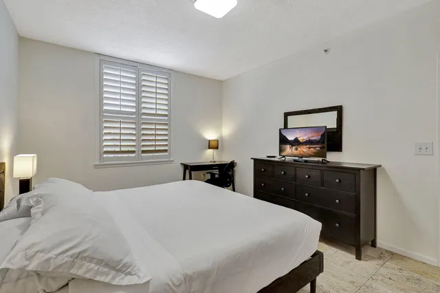 a bedroom with a bed and a flat tv screen on a dresser