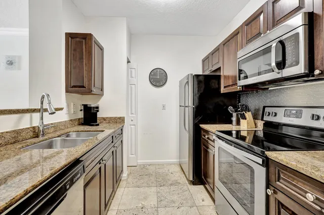 a kitchen with stainless steel appliances granite countertop a sink stove and refrigerator