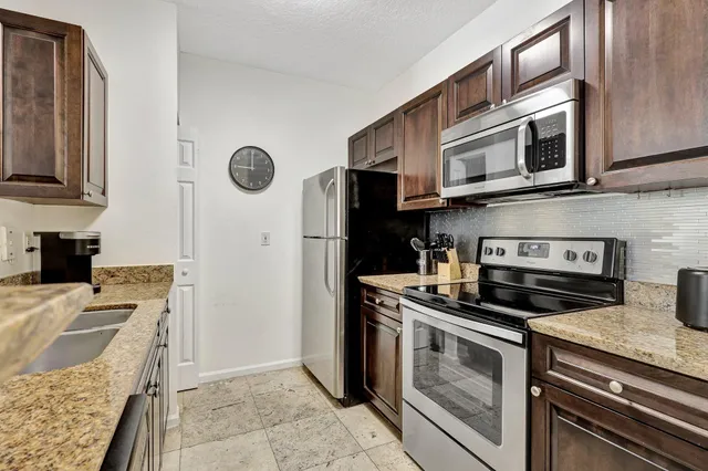 a kitchen with stainless steel appliances granite countertop a sink stove and refrigerator
