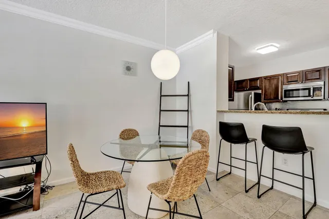 a kitchen with stainless steel appliances kitchen island granite countertop a dining table chairs and a refrigerator