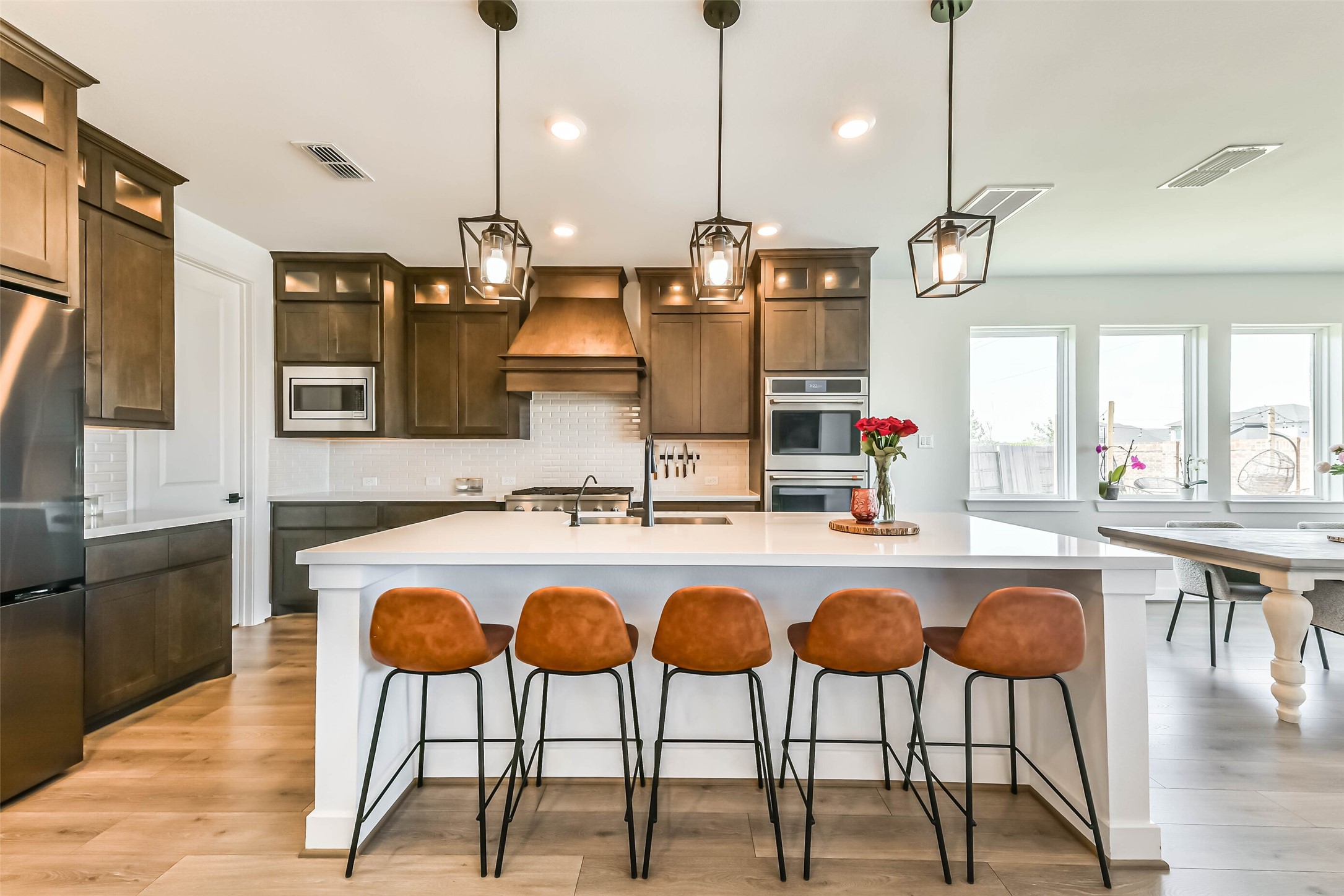 1612 Dayton Rdg Circle Friendswood, TX 77546 - Photo 11 of 50 Modern kitchen featuring dark wood cabinets, a large island with seating for four, stainless steel appliances, and stylish pendant lighting. Bright and open with ample natural light