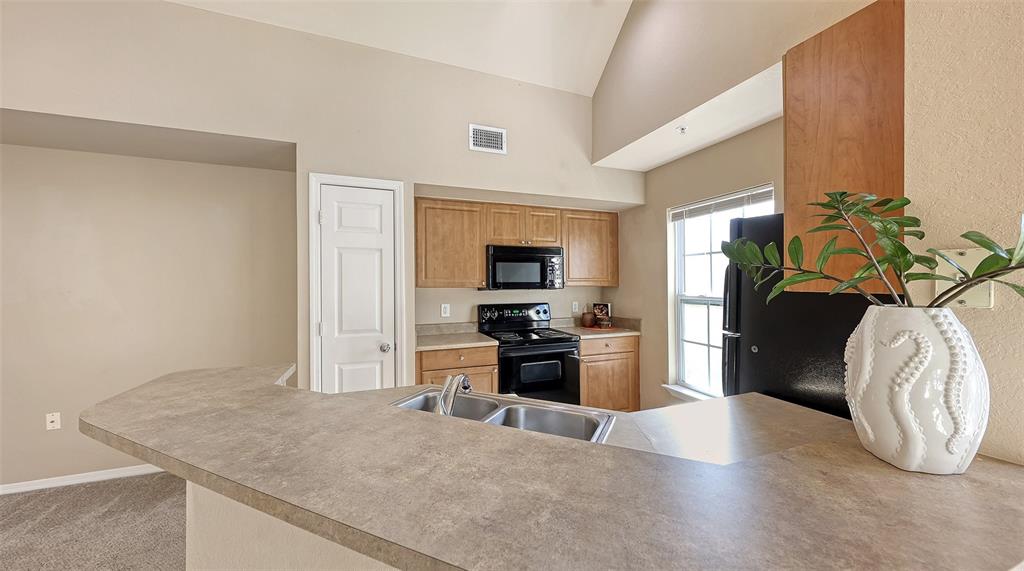5520 Rosehill Road, Unit 203 Sarasota, FL 34233 - Photo 11 of 46 a kitchen with stainless steel appliances kitchen island granite countertop a refrigerator a stove and a sink with granite countertops