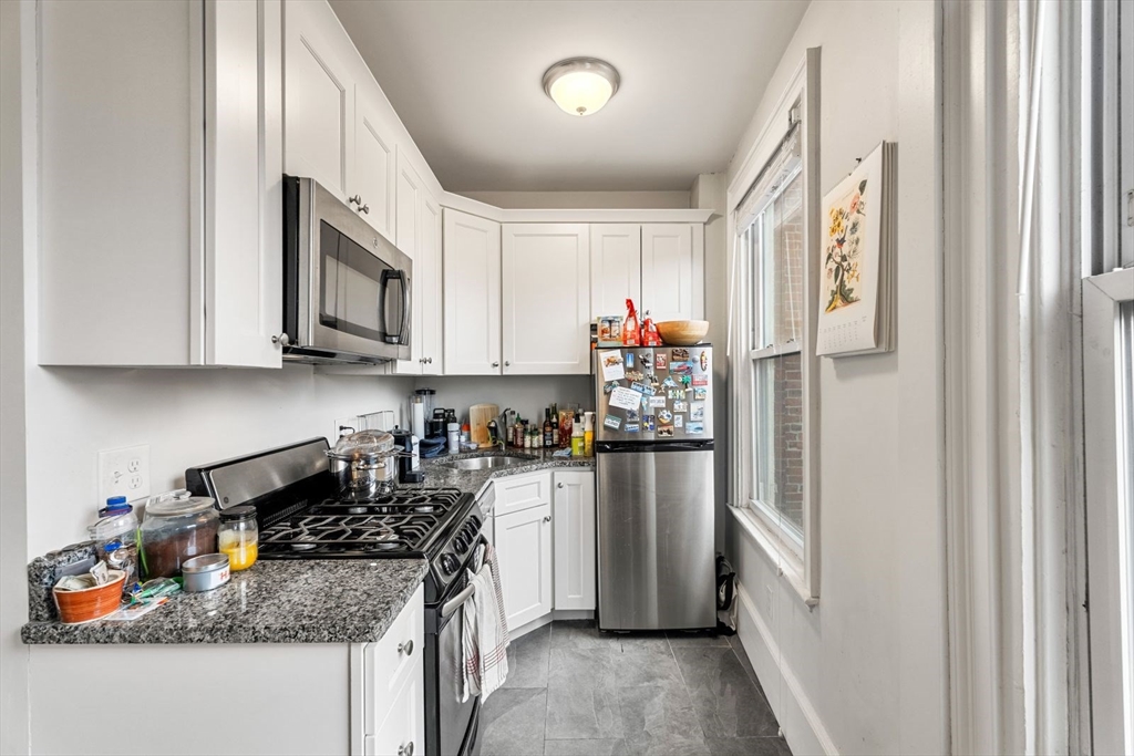 62 West Cedar Street, Unit 3 Boston, MA 02114 - Photo 8 of 18 a kitchen with stainless steel appliances granite countertop a refrigerator stove microwave and sink