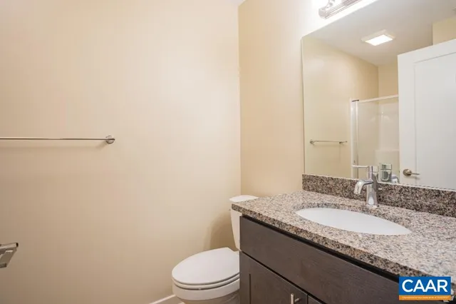 a bathroom with a granite countertop sink a toilet and a mirror
