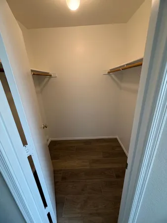 an empty room with wooden floor and a ceiling fan