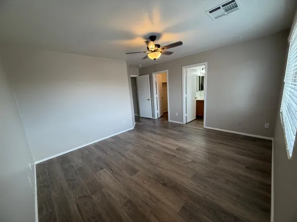 an empty room with wooden floor and windows