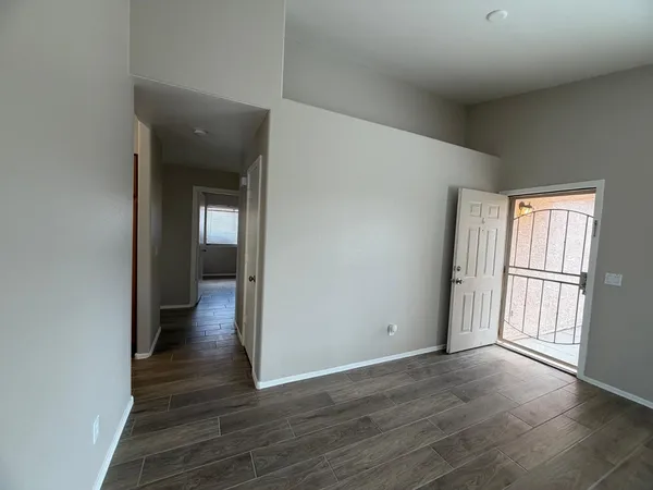 a view of an empty room with wooden floor and a window