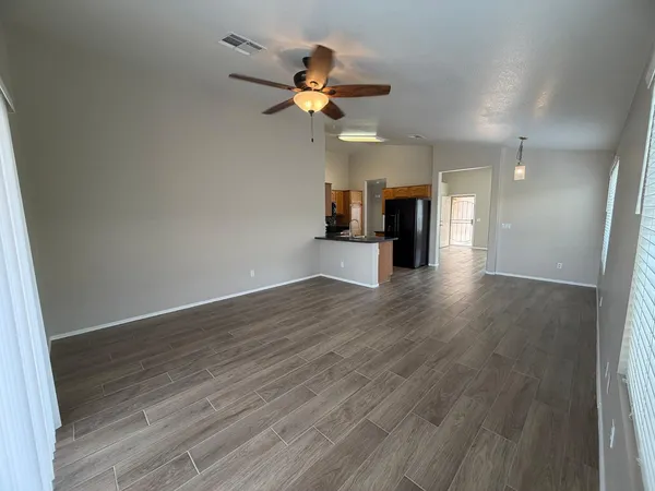 a view of an empty room with a window and wooden floor
