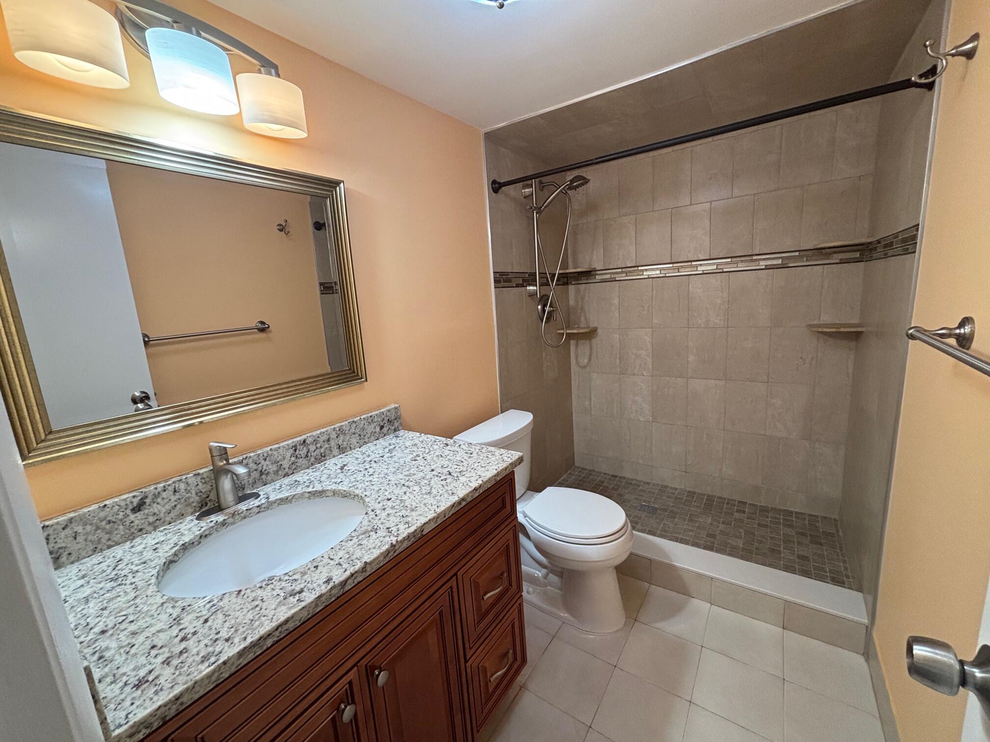 4411 Trevi Court, Unit 106 Lake Worth, FL 33467 - Photo 11 of 21 a bathroom with a granite countertop sink toilet and shower