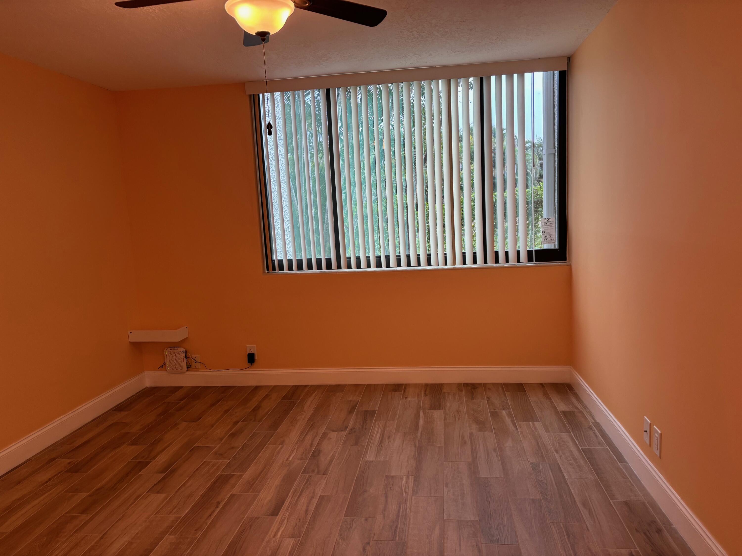 4411 Trevi Court, Unit 106 Lake Worth, FL 33467 - Photo 12 of 21 wooden floor and window in an empty room