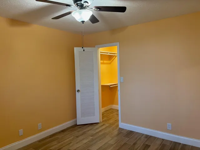 an empty room with wooden floor and ceiling fan