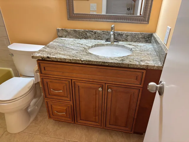a bathroom with a granite countertop sink and a toilet