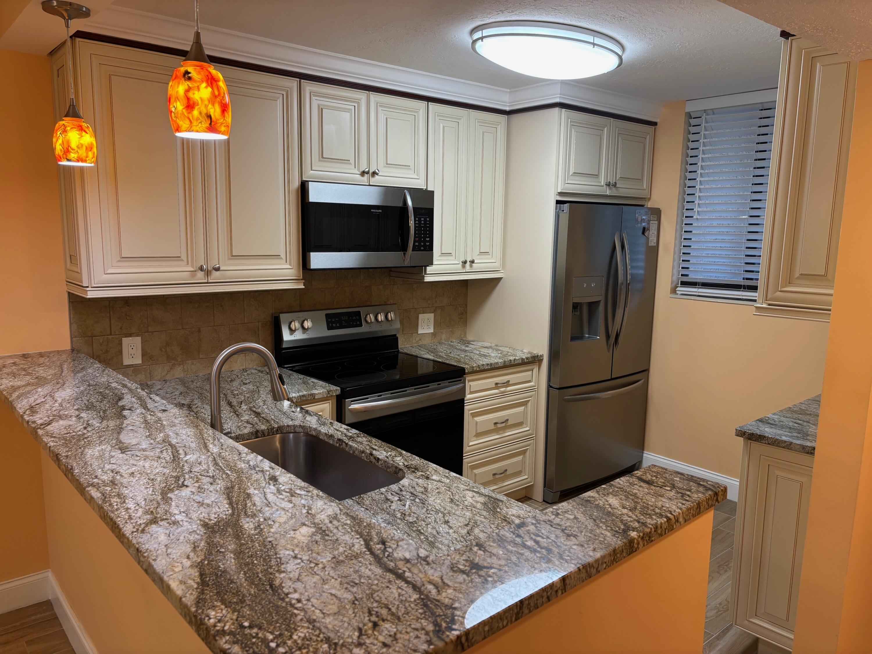 4411 Trevi Court, Unit 106 Lake Worth, FL 33467 - Photo 2 of 21 a kitchen with stainless steel appliances granite countertop a sink a refrigerator and a stove