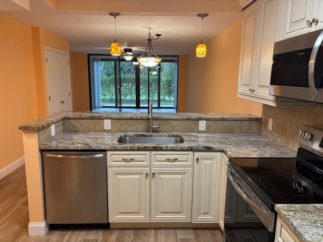a kitchen with granite countertop a sink stove and cabinets