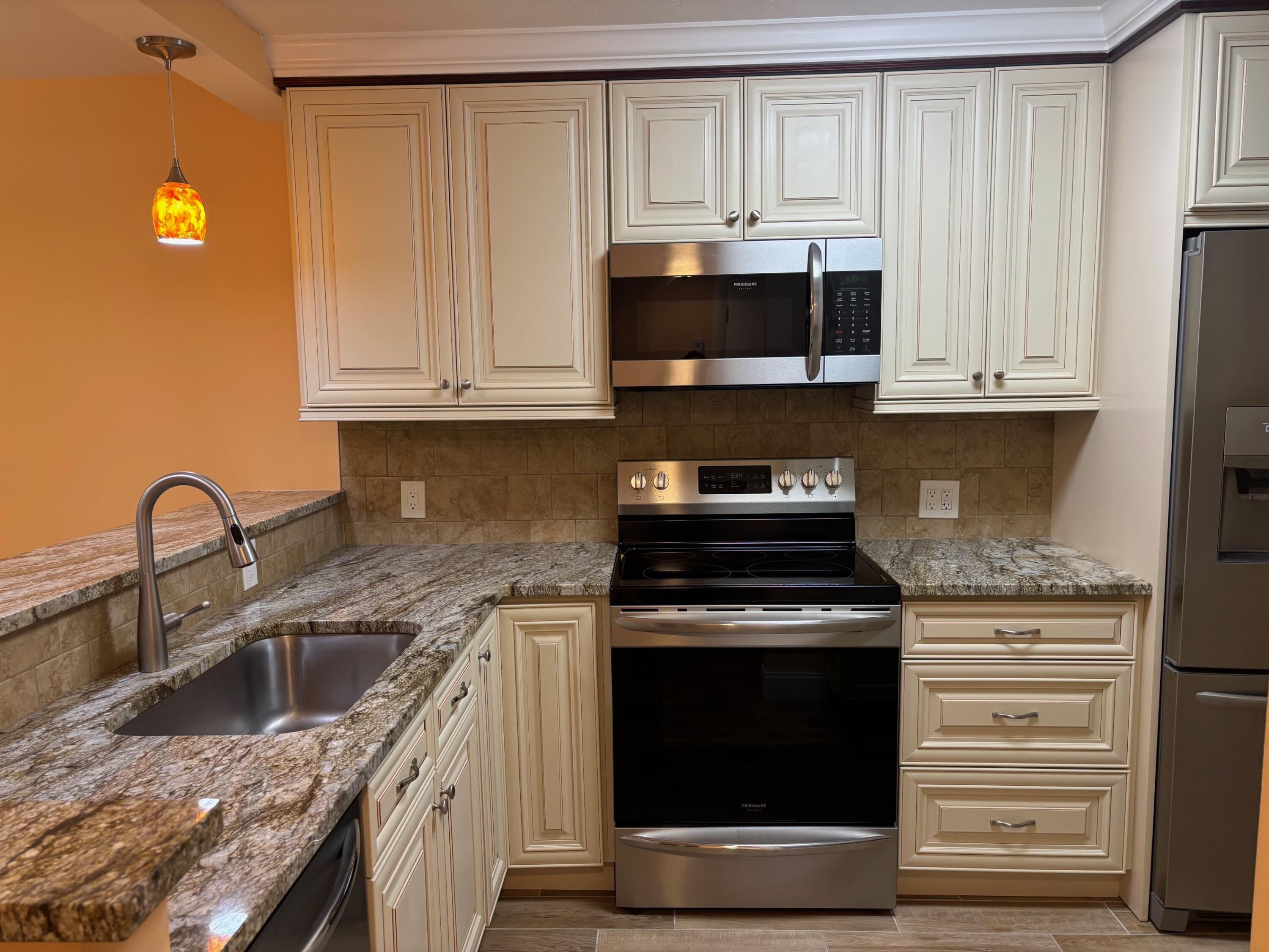4411 Trevi Court, Unit 106 Lake Worth, FL 33467 - Photo 4 of 21 a kitchen with stainless steel appliances granite countertop a stove a sink and a microwave