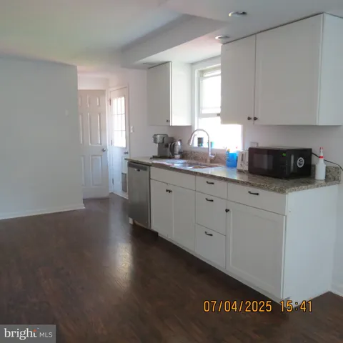 a kitchen with granite countertop white cabinets a sink and dishwasher