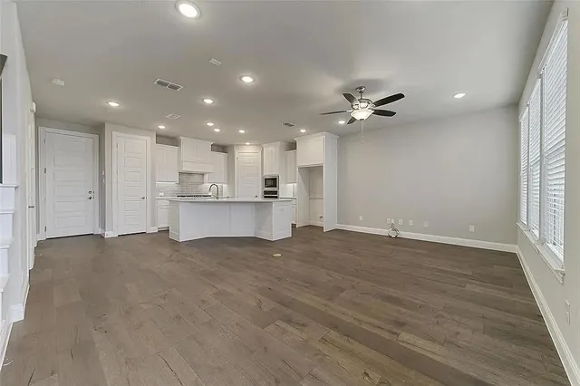 a view of an empty room with a window and wooden floor