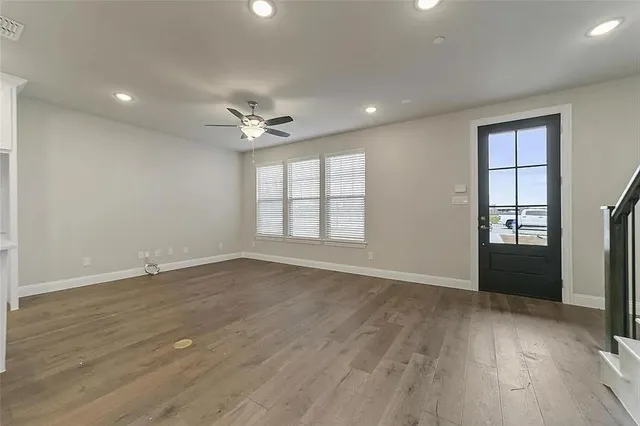 a view of an empty room with wooden floor a ceiling fan