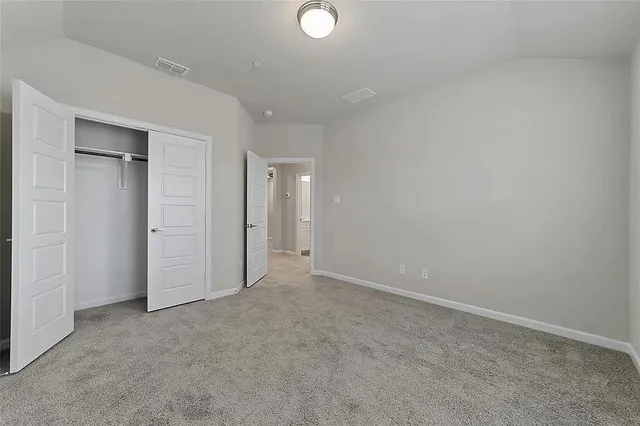 an empty room with chandelier fan and windows