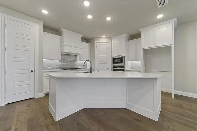 a kitchen with white cabinets appliances and center island