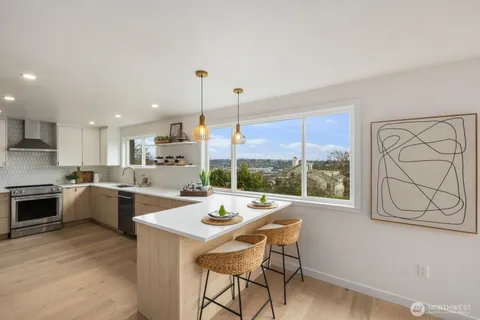 a open dining room with stainless steel appliances kitchen island granite countertop a sink a stove a dining table and chairs with wooden floor