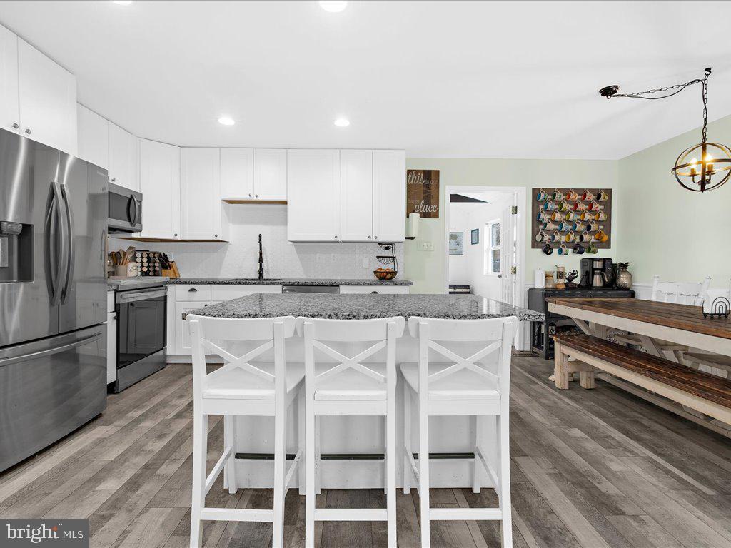 251 Ullman Road Pasadena, MD 21122 - Photo 8 of 29 a kitchen with stainless steel appliances kitchen island granite countertop a stove a refrigerator and white cabinets with wooden floor