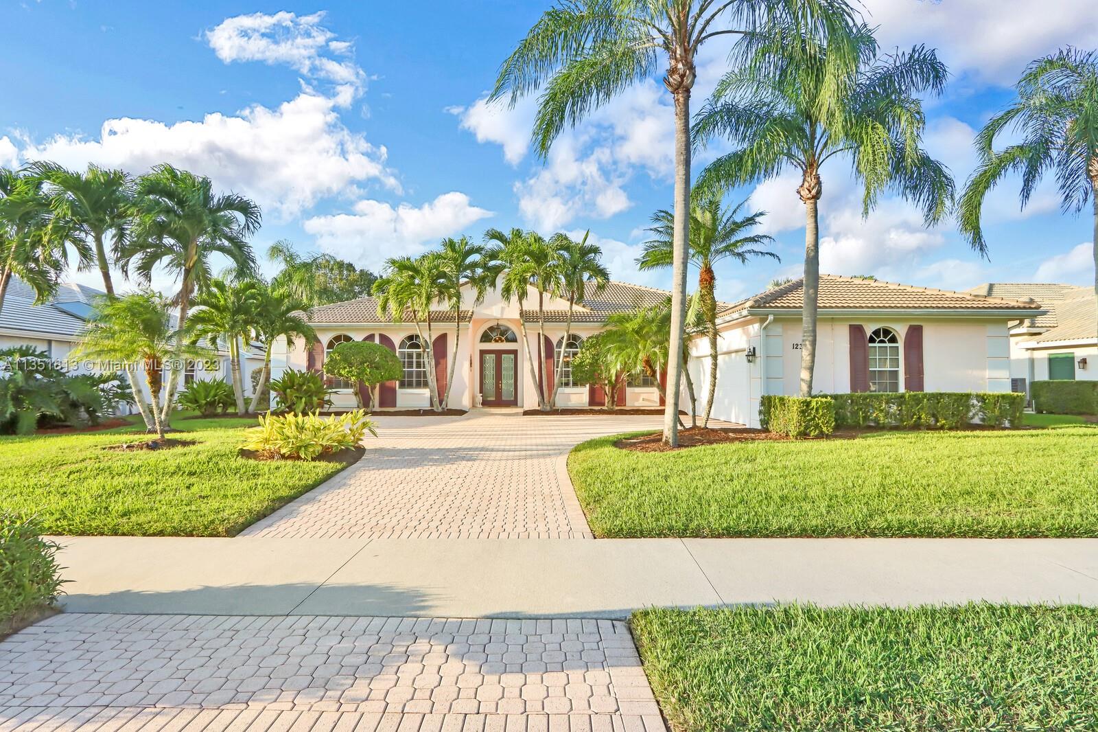 front view of a house with a yard and palm trees