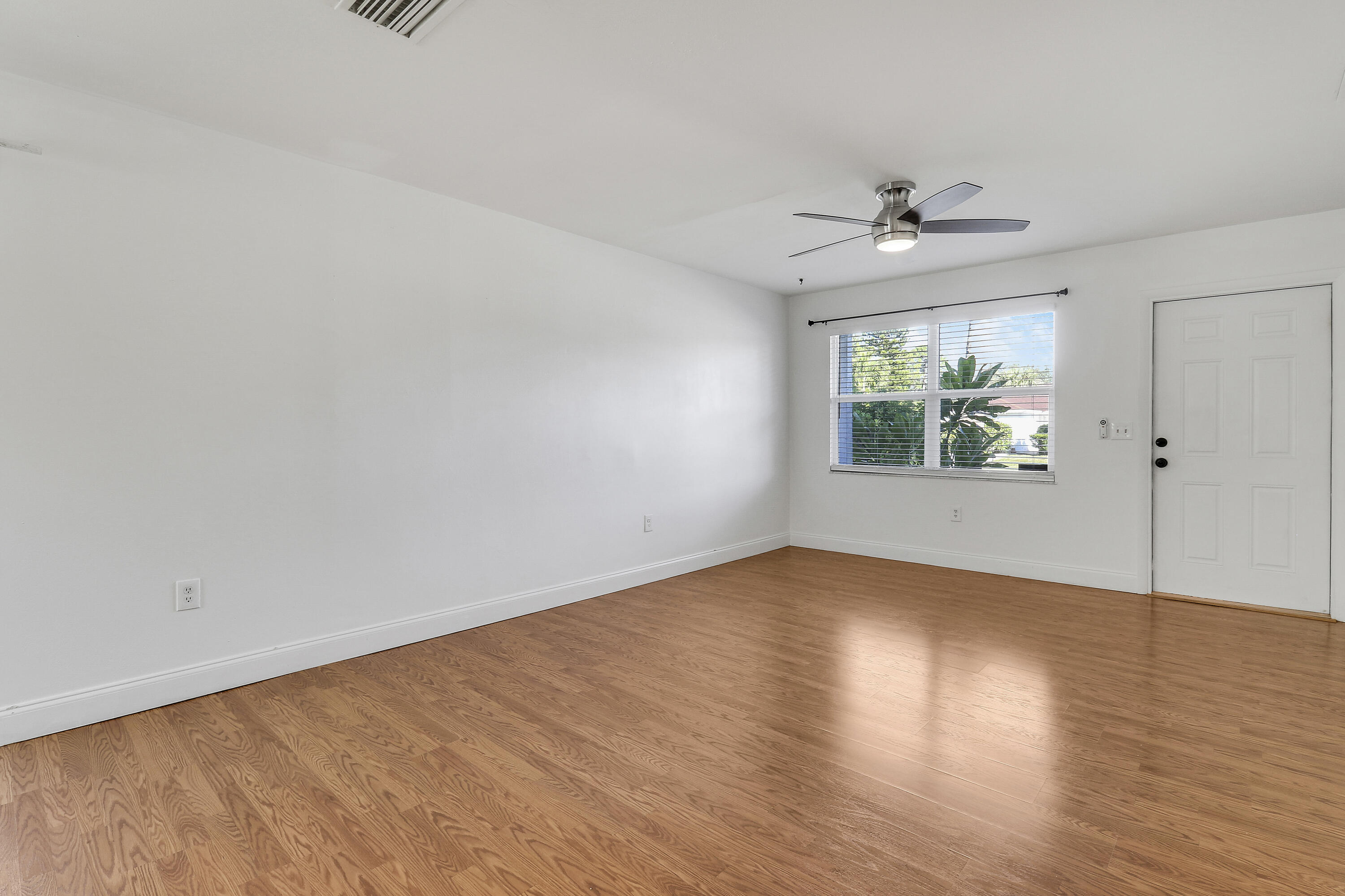 6264 Allen Street Jupiter, FL 33458 - Photo 20 of 27 an empty room with wooden floor chandelier fan and windows