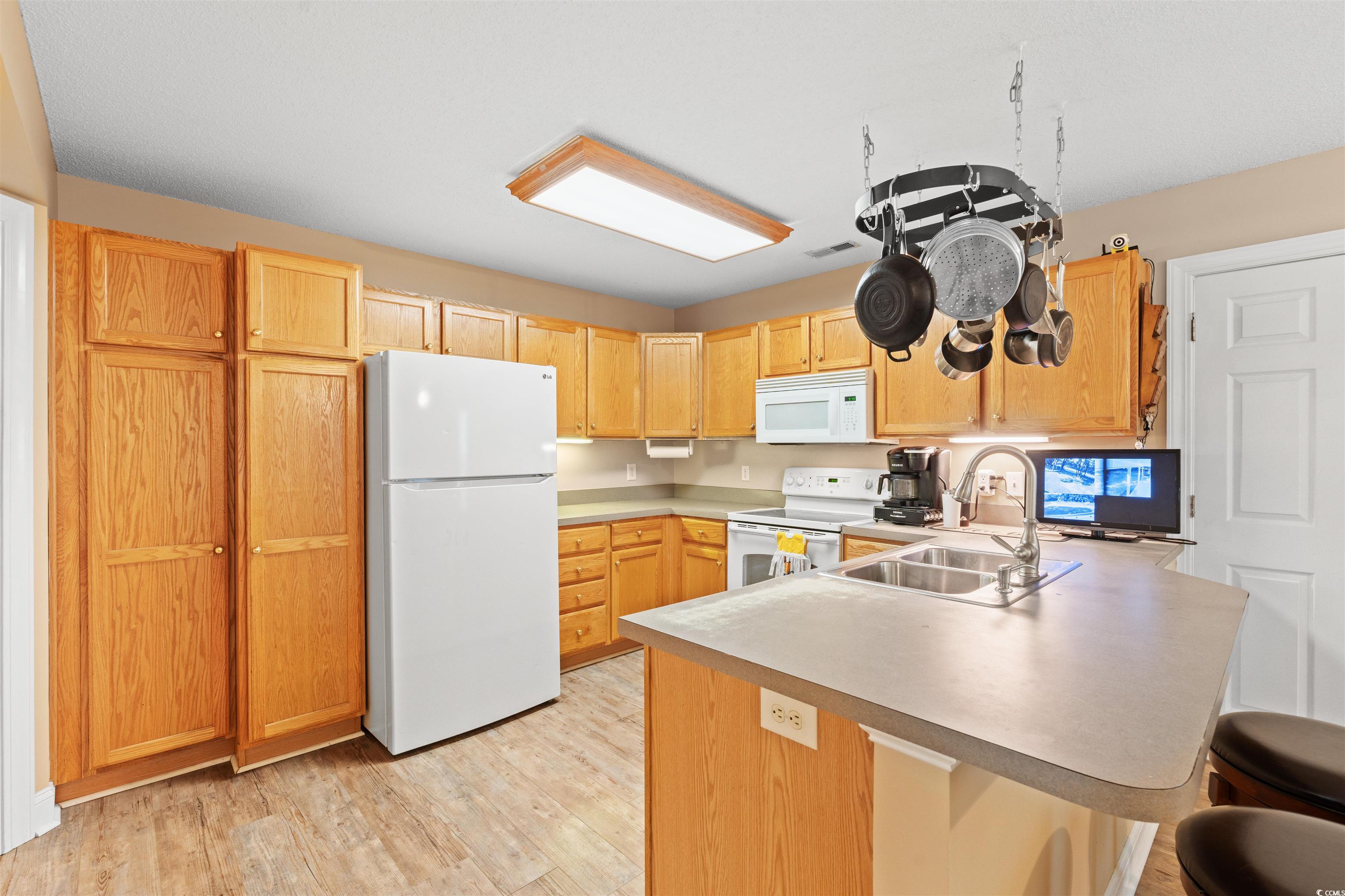 938 Fox Hollow Road Conway, SC 29526 - Photo 8 of 39 Kitchen with white appliances, a peninsula, light wood finished floors, a kitchen breakfast bar, and light countertops