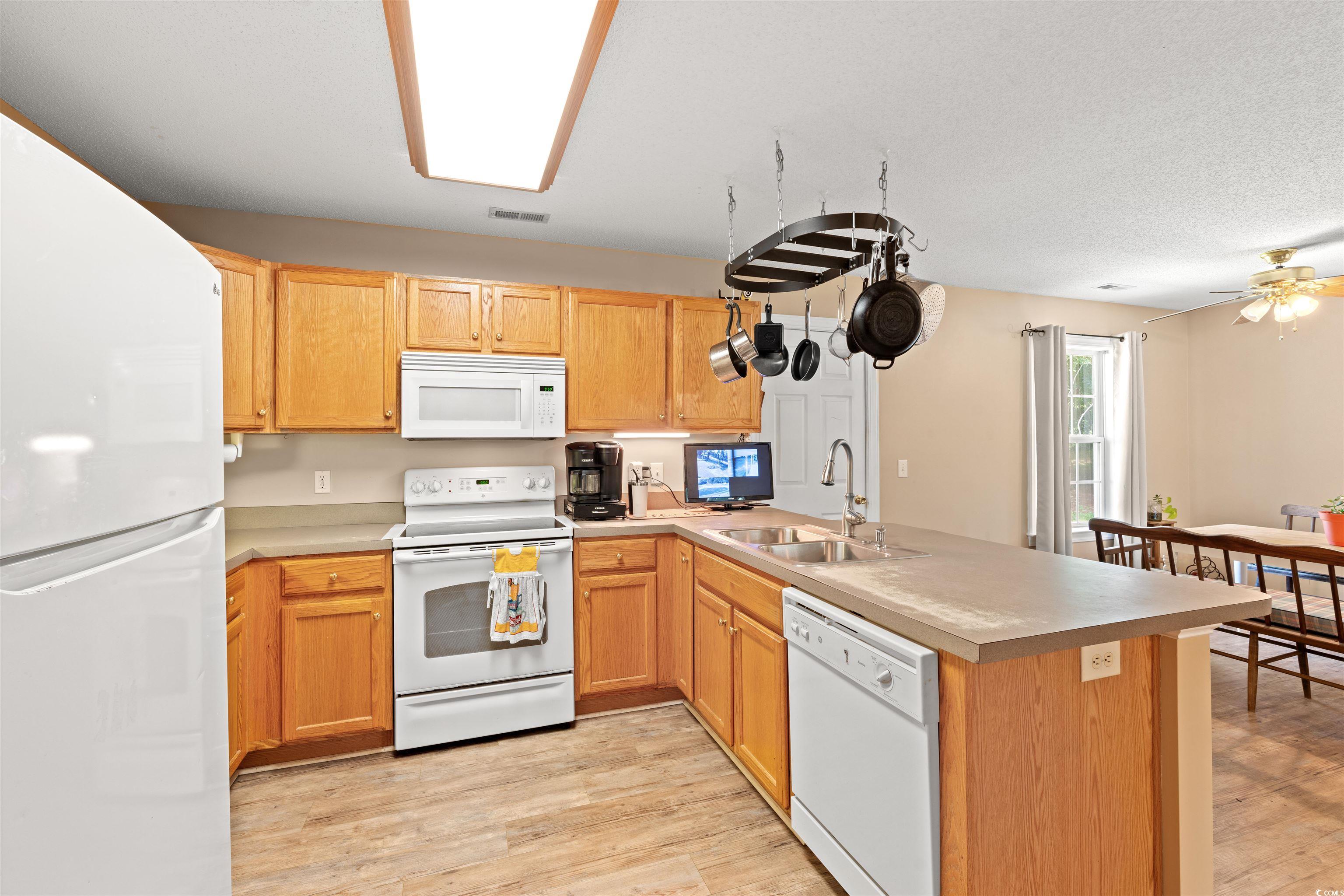 938 Fox Hollow Road Conway, SC 29526 - Photo 9 of 39 Kitchen with white appliances, a peninsula, light wood-style flooring, ceiling fan, and light countertops