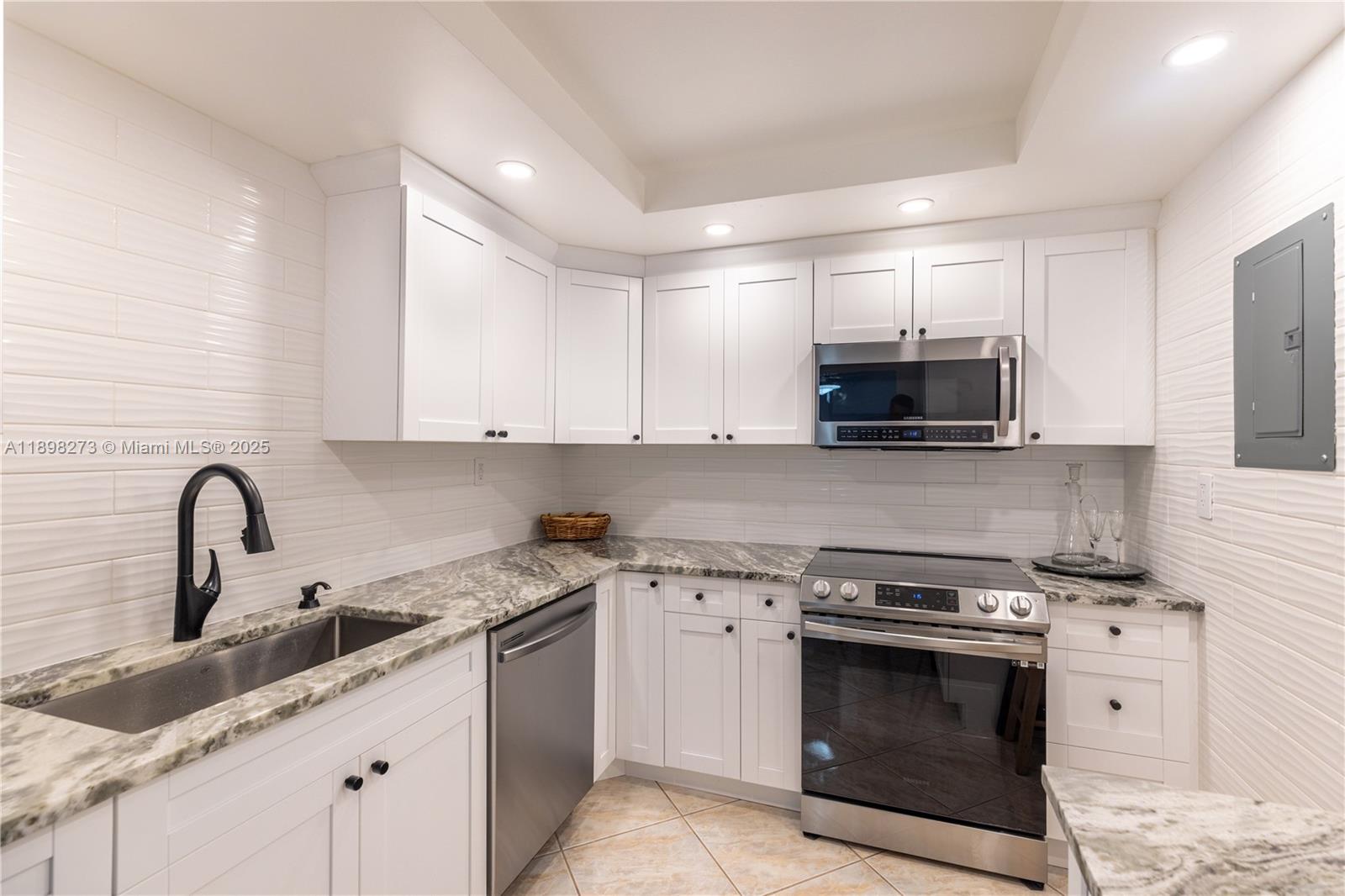 525 North Ocean Boulevard, Unit 1820 Pompano Beach, FL 33062 - Photo 2 of 18 a kitchen with stainless steel appliances granite countertop a sink dishwasher a stove and a microwave oven with white cabinets
