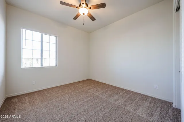 an empty room with a chandelier fan and windows