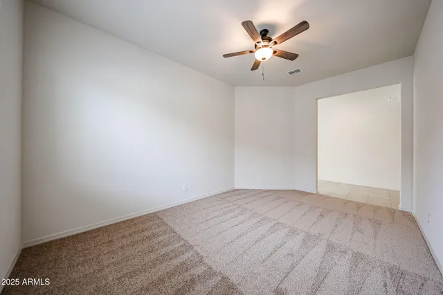 an empty room with chandelier fan and windows