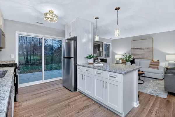 a kitchen with stainless steel appliances granite countertop a stove a refrigerator a oven and a wooden floors