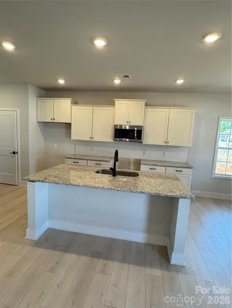 a large kitchen with stainless steel appliances granite countertop a sink a stove a refrigerator a center island and cabinets