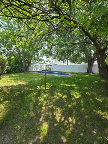 a backyard of a house with lots of plants and large tree