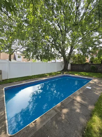 a view of outdoor space with swimming pool and trees in the background