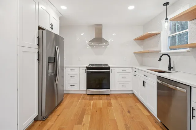 a kitchen with stainless steel appliances granite countertop a refrigerator and a stove top oven