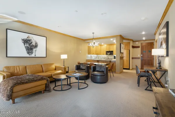 a living room with furniture a table and kitchen view